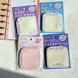 Könnte beinhalten: Vier bunte Haftnotizblöcke mit niedlichen Tierillustrationen. Die Blöcke sind mit "Lazy Cat Memo", "Cat Weekly Note", "Cute Paws Prints" und "Sweet Puppy Kiss" beschriftet. Jeder Block enthält 30 Blatt.