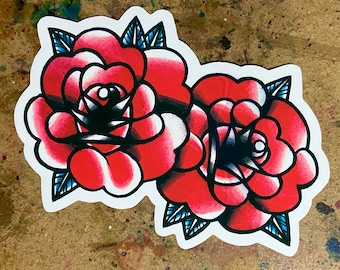 May include: Two red roses with black outlines and blue leaves. The roses are stylised and have a traditional tattoo look.