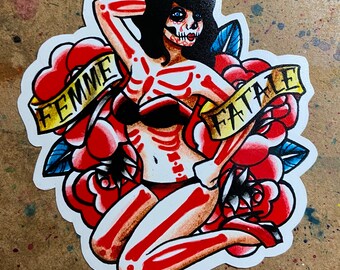 May include: A sticker featuring a skeleton woman with a skull face, wearing a red bikini and sitting on a red rose. The sticker has the words "Femme Fatale" written on a yellow banner.