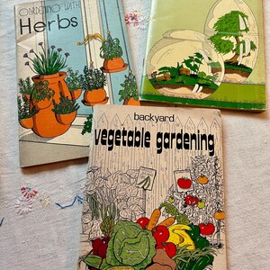 May include: Three softcover gardening books titled Gardening with Herbs, Gardening with Terrariums, and Backyard Vegetable Gardening. The covers feature colorful illustrations of potted herbs, glass terrariums, and a basket of fresh vegetables.