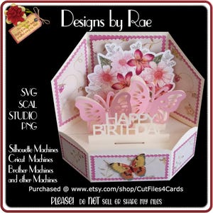 May include: A pop-up birthday card with a butterfly and floral design. The card features pink butterflies, flowers, and the words "Happy Birthday." The card is decorated with a floral pattern and the text "Designs by Rae."