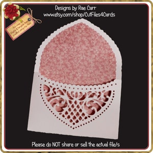 May include: A white card with a delicate, intricate, cut-out design in the shape of a heart. The card is folded to create a pocket for a smaller card or a gift. The pocket is lined with a pink patterned paper. The text "You may sell Digital & tangible items created using my files" is on a small tag in the upper left corner. The text "Designs by Rae Carr www.etsy.com/shop/CutFiles4Cards" is at the top of the image. The text "Please do NOT share or sell the actual file/s" is at the bottom of the image.