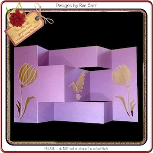 May include: A purple layered card with a pop-up hummingbird and flowers. The card is decorated with gold accents. The text "You may sell tangible items created using my files" and "Designs by Rae Carr" are visible on the card. The text "PLEASE... do NOT sell or share the actual file/s" is visible at the bottom of the card.