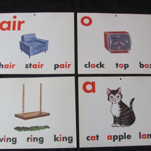 May include: Four flashcards with red letters and illustrations. The letters are 'a', 'i', 'o', and 'air'. The illustrations are a chair, a swing, a clock, and a cat. The words below each illustration are 'chair, stair, pair', 'swing, ring, king', 'clock, top, box', and 'cat, apple, lamp'.