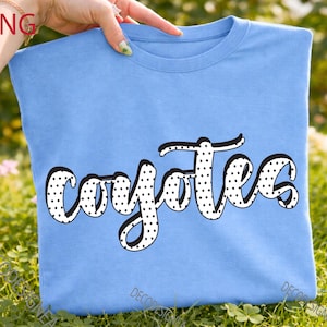 Peut inclure: Un t-shirt bleu clair avec le mot coyotes imprimé en blanc à pois noirs et doté d'un contour noir épais. Le texte est écrit dans un style cursif au centre du t-shirt, qui présente une encolure ronde classique et des manches courtes.