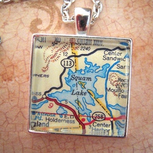 May include: Silver-toned necklace with a square pendant featuring a map of Squam Lake, New Hampshire. The map includes roads, water features, and the number 113. The pendant is approximately 1 inch square.