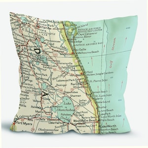 May include: A decorative pillow featuring a vintage map of Florida, with cities like Orlando, West Palm Beach, and Fort Myers. The pillow has a light green background and a detailed map design.