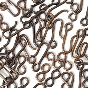 May include: A pile of antique brass S-shaped hooks. The hooks are all the same size and shape, and they are arranged in a random pattern.