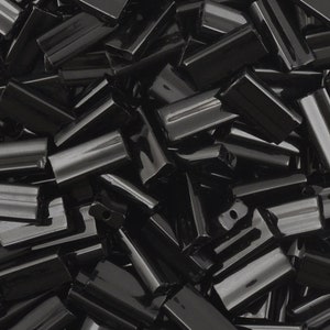 May include: A large pile of black glass beads, each bead is a long, thin rectangle with a slight curve.