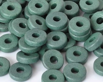 May include: A collection of numerous small, round, flat beads in a muted sage green color. Each bead features a smooth, matte finish and a centered circular hole, creating a uniform appearance across the entire pile of loose, circular components.