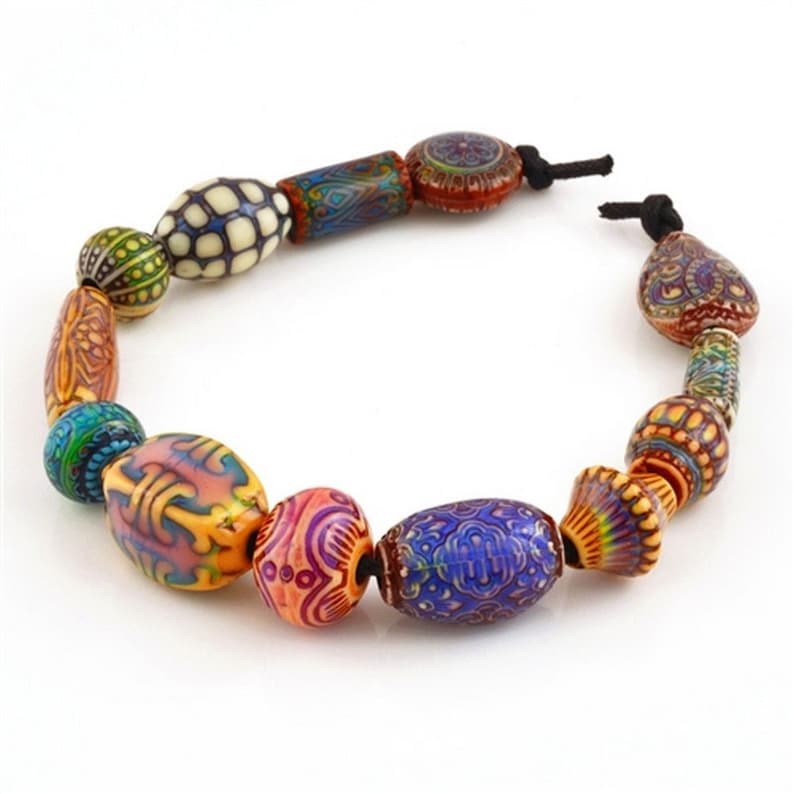 May include: A vibrant beaded necklace with a selection of patterned beads in blue, orange, green, and red. The beads are strung on a black cord, creating a unique and eye-catching accessory.