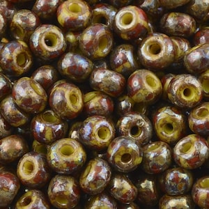 May include: A collection of round beads with a hole through the center. The beads have a mottled appearance with a mix of colors, including brown, yellow, and red. The beads are likely used for jewelry making or other crafts.