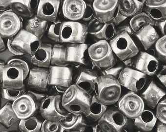 May include: A close-up of a pile of silver metal beads with a circular design and a hole in the center. The beads are perfect for jewelry making or other craft projects.