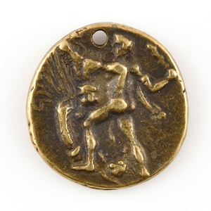 May include: A round, antique-style bronze pendant with a hole at the top. The pendant features a relief of a figure with outstretched arms and a detailed background. The bronze has a weathered, aged appearance.