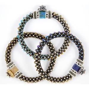 以下が含まれることがあります： 異なる色の組み合わせのビーズブレスレット3本。ブレスレットは、青、紫、金色の虹色をした小さなビーズで作られています。各ブレスレットには、装飾的な金属製の留め具が付いています。