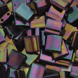 May include: A close-up of a pile of iridescent black square glass beads. The beads have a metallic sheen and are perfect for jewelry making.