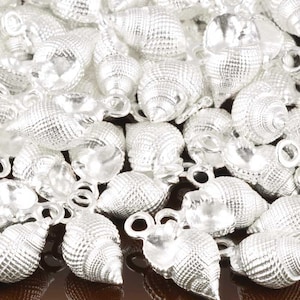 May include: A pile of silver-colored seashell charms with a loop for attaching to jewelry or other crafts.