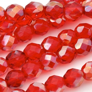 May include: A strand of red faceted glass beads. The beads are round and have a shiny, iridescent finish.