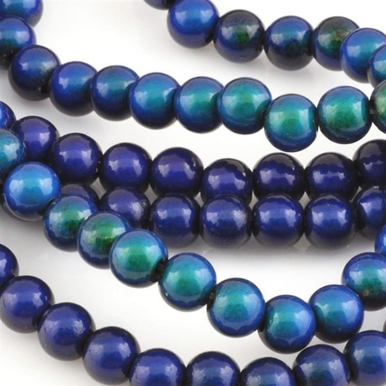 May include: Strands of round wooden beads in shades of blue and teal. The beads have a glossy finish and are strung together, creating a textured and colorful pattern. These beads are suitable for jewelry making and craft projects.
