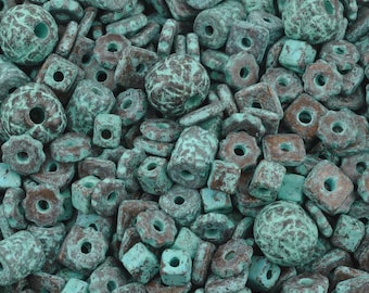 May include: A collection of turquoise and brown beads in various shapes, including round, square, and floral designs. The beads have a weathered, textured appearance, suggesting an aged or antique aesthetic. The beads are scattered, filling the frame.