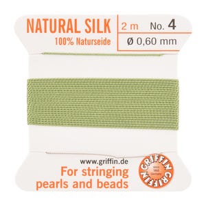 May include: A spool of natural silk thread, color number 4, in a light green hue. The label reads "NATURAL SILK" and "100% Naturseide". The thread is 0.60 mm in diameter and 2 meters long. The label also states "For stringing pearls and beads".