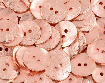 May include: A collection of round, metallic rose gold buttons, each featuring a textured, hammered surface and two central holes for attachment. The buttons are arranged in a dense, overlapping pile, showcasing their reflective finish.