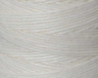May include: A close-up of a spool of white cotton twine. The twine is tightly wound and has a smooth, natural texture.