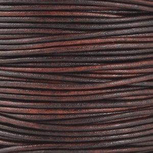May include: Close-up of a spool of dark brown leather cord. The cord has a slightly distressed appearance with variations in color, ranging from deep brown to reddish-brown. The texture appears smooth with a slight sheen.