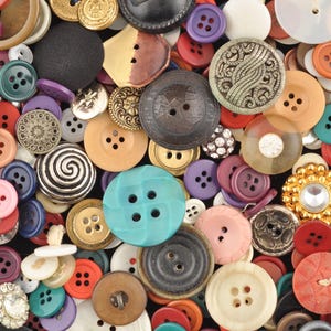 May include: A large collection of assorted sewing buttons in various shapes, sizes, and colors, including metallic, plastic, and wooden materials, featuring different textures, patterns, and hole configurations scattered across the frame.