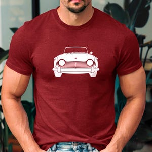 Puede incluir: Camiseta granate con un contorno blanco de un coche descapotable cl&aacute;sico. El dise&ntilde;o del coche incluye faros redondos, una parrilla delantera y un perfil bajo. La camiseta es de material suave.