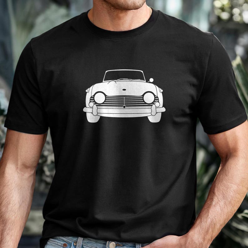 Puede incluir: Camiseta negra con un dibujo lineal blanco de un coche descapotable cl&aacute;sico. El coche tiene faros redondos y un parachoques delantero prominente. El dise&ntilde;o est&aacute; centrado en la camiseta, ofreciendo una est&eacute;tica limpia y minimalista. La camiseta es de material suave.