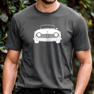 Puede incluir: Camiseta gris oscuro con un contorno blanco de un coche descapotable cl&aacute;sico. Se muestra la vista frontal del coche, con faros, parrilla y parabrisas. La camiseta est&aacute; hecha de un material suave.