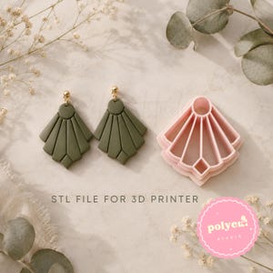 Può includere: Un paio di orecchini a ventaglio verde oliva con perni dorati e un tagliabiscotti in plastica rosa chiaro abbinato. Il testo STL FILE FOR 3D PRINTER è stampato in nero sotto gli oggetti e un logo circolare rosa riporta polyclay studio.