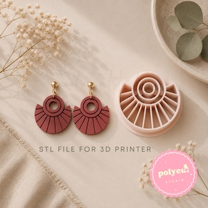Può includere: Due orecchini a forma di ventaglio rosso scuro con perni dorati e uno stampo da taglio in plastica rosa chiaro per stampante 3D. Il testo STL FILE FOR 3D PRINTER è stampato al centro. Il design presenta una parte superiore circolare con linee.