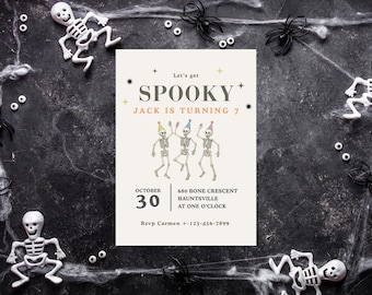 May include: Halloween-themed invitation with the text "SPOOKY" and "Jack is turning 7". The invitation features dancing skeleton illustrations and is surrounded by plastic skeletons, spiders, and spiderwebs on a dark background.