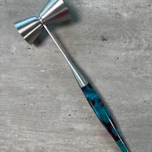 Könnte beinhalten: Ein silberner Jigger mit einem blau-schwarzen Marmor-Griff. Der Jigger hat zwei Messbecher.
