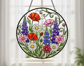 May include: A round stained glass panel featuring a colorful floral design. The panel showcases red poppies, white daisies, pink and purple lupines, and other flowers, all set against a clear background. It is framed by a black metal border and suspended by a chain.