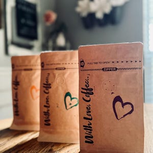 May include: Three brown paper bags with the text "With Love, Coffee." printed on them. The bags have a heart design and a zipper closure. The text "Pull Tab to Open" is printed on the top of the bag.