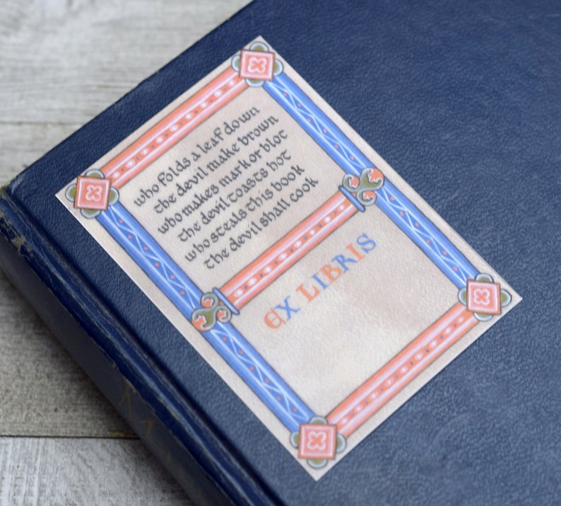 Pode incluir: Um livro com um ex libris decorativo que diz "who folds a leaf down the devil make brown who makes mark or blot the devil toasts hot who steals this book the devil shall cook EX LIBRIS".