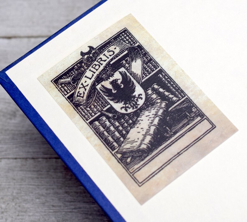 K&ouml;nnte beinhalten: Ein antiker Exlibris mit einer Schwarzwei&szlig;illustration eines Vogels, B&uuml;chern und dem Text "Ex-Libris".