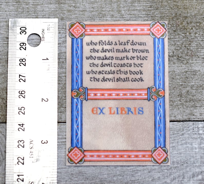Pode incluir: Um ex libris com uma borda decorativa em tons de azul, laranja e vermelho. O texto diz: "who folds a leaf down the devil make brown who makes mark or blot the devil toasts hot whos steals this book the devil shall cook" e "EX LIBRIS".