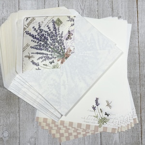 May include: A stationery set with lavender and butterfly motifs. The set includes white envelopes, lined paper, and decorative paper with lavender sprigs, dragonflies, and butterflies. The envelopes feature a lavender bouquet design and the words "DE LAVANDE".