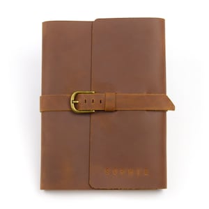 May include: A brown leather journal with a brass buckle closure and the name "SOPHIE" embossed on the front cover.