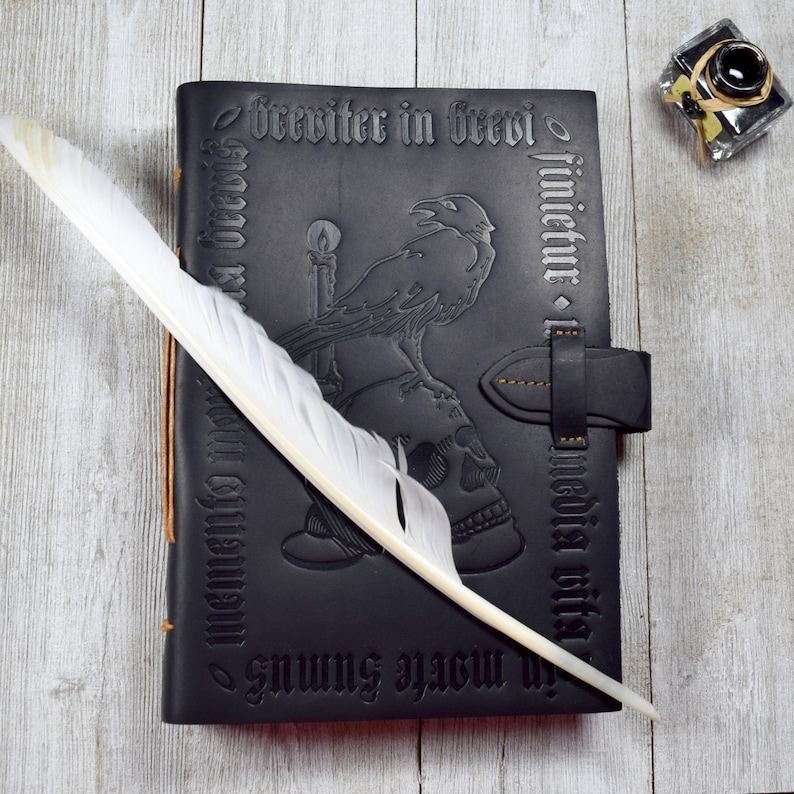 The dark Gothic journal rests on a table with a feather quill pen and ink bottle.
