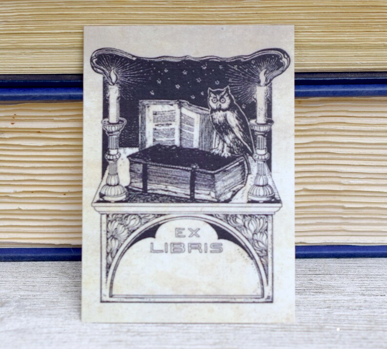 May include: A black and white illustration of an owl perched on a book with candles on either side. The image is framed with a decorative border and includes the text "Ex Libris".