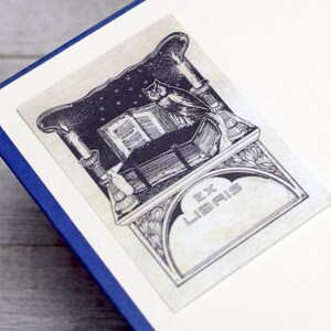 May include: Black and white illustration of an owl perched on a book with a candle and the text "Ex Libris" on a decorative background.