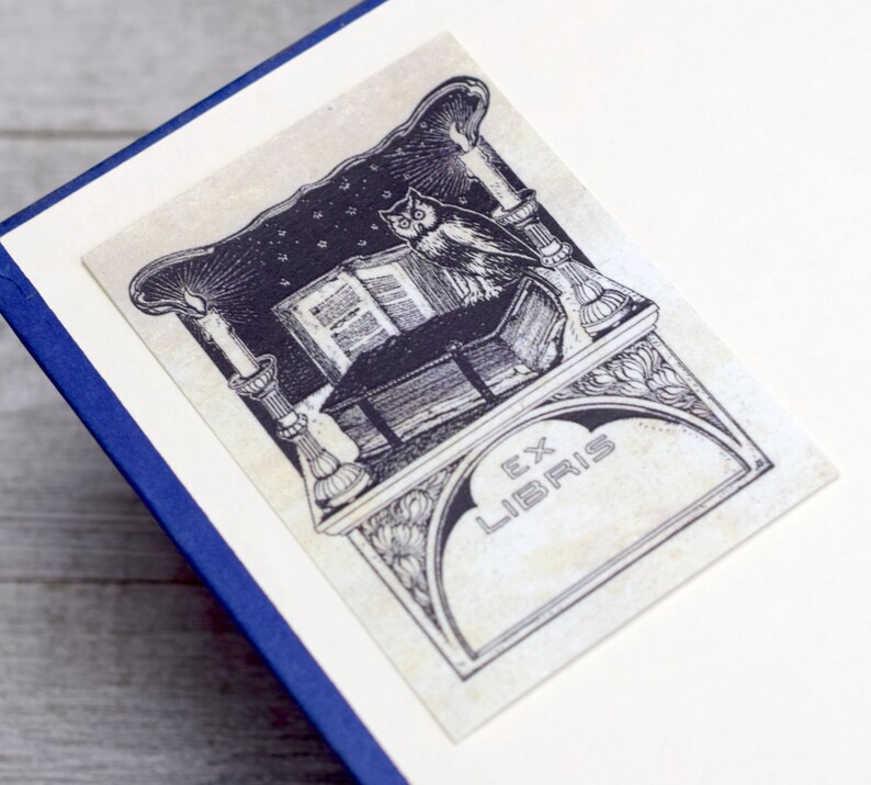 May include: Black and white illustration of an owl perched on a book with a candle and the text "Ex Libris" on a decorative background.