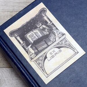 May include: A vintage bookplate featuring an owl perched on a book, candles, and the text "Ex Libris".
