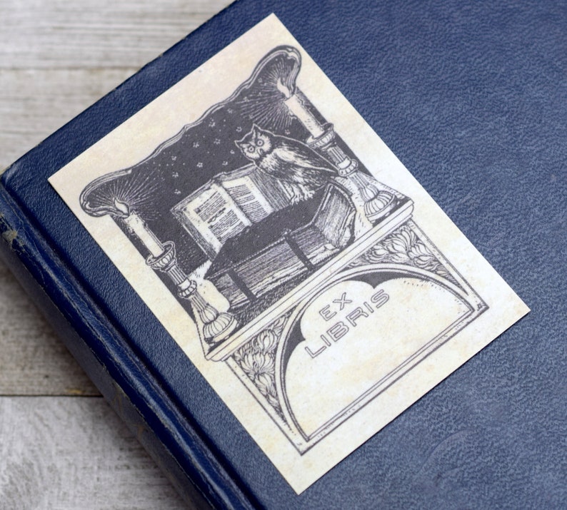 May include: A vintage bookplate featuring an owl perched on a book, candles, and the text "Ex Libris".
