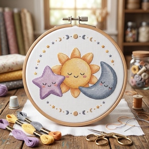 May include: A cross-stitch embroidery hoop featuring a sun, star, and moon design. The sun is yellow, the star is purple, and the moon is blue. The embroidery is set in a wooden hoop, with embroidery floss and scissors nearby.